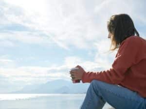 Person Sitting in Front of Body of Water