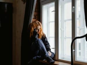 Woman in Black Leather Jacket Sitting on Brown Wooden Floor
